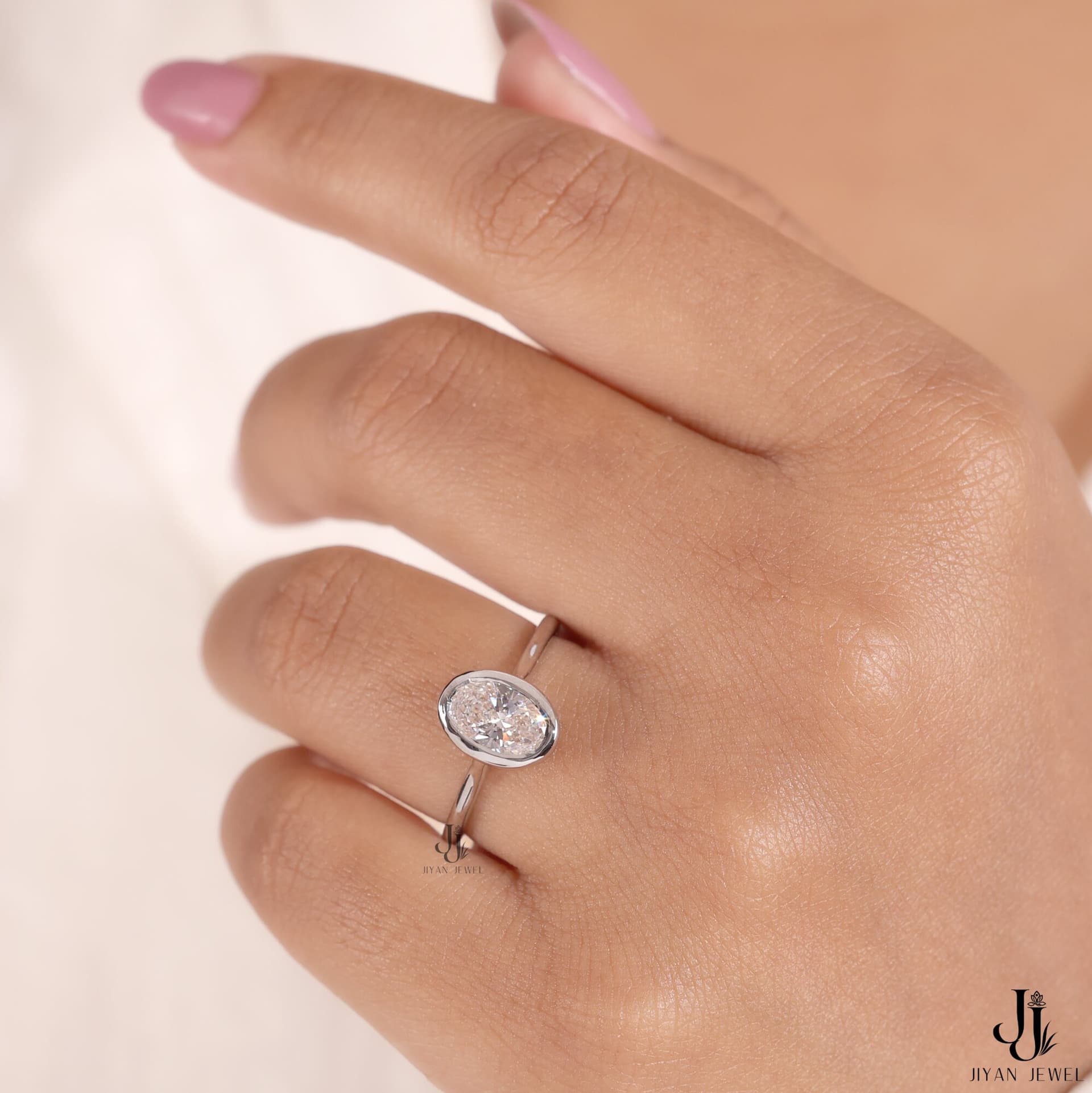 Bezel-set oval moissanite solitaire in white gold worn on the hand